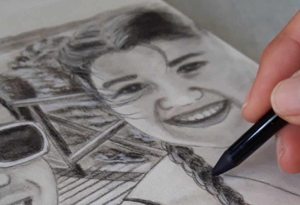 Hand mit Kohlestift zeichnet Portrait