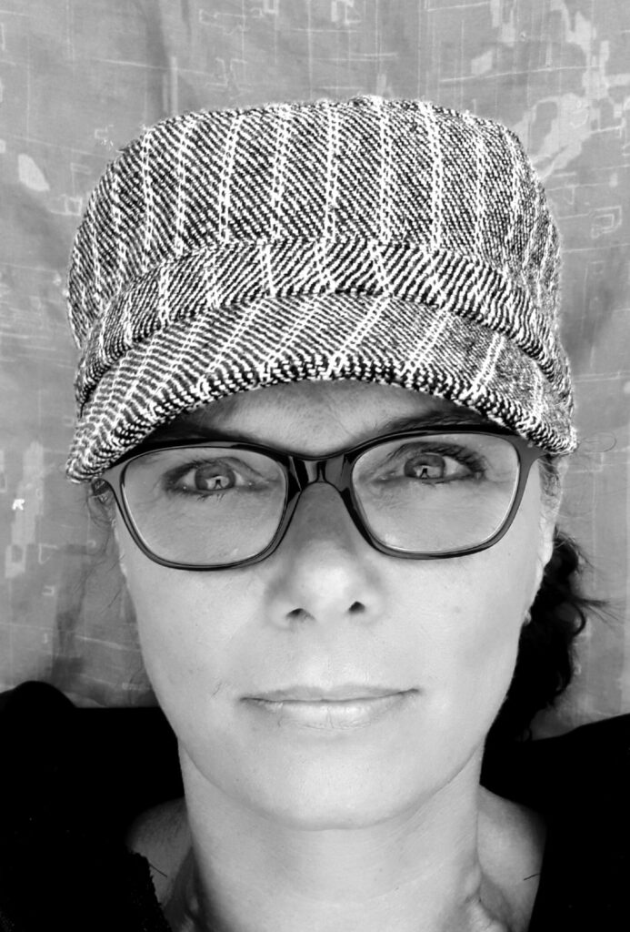 Junge Frau mit Brille und Cap lächelt freundlich